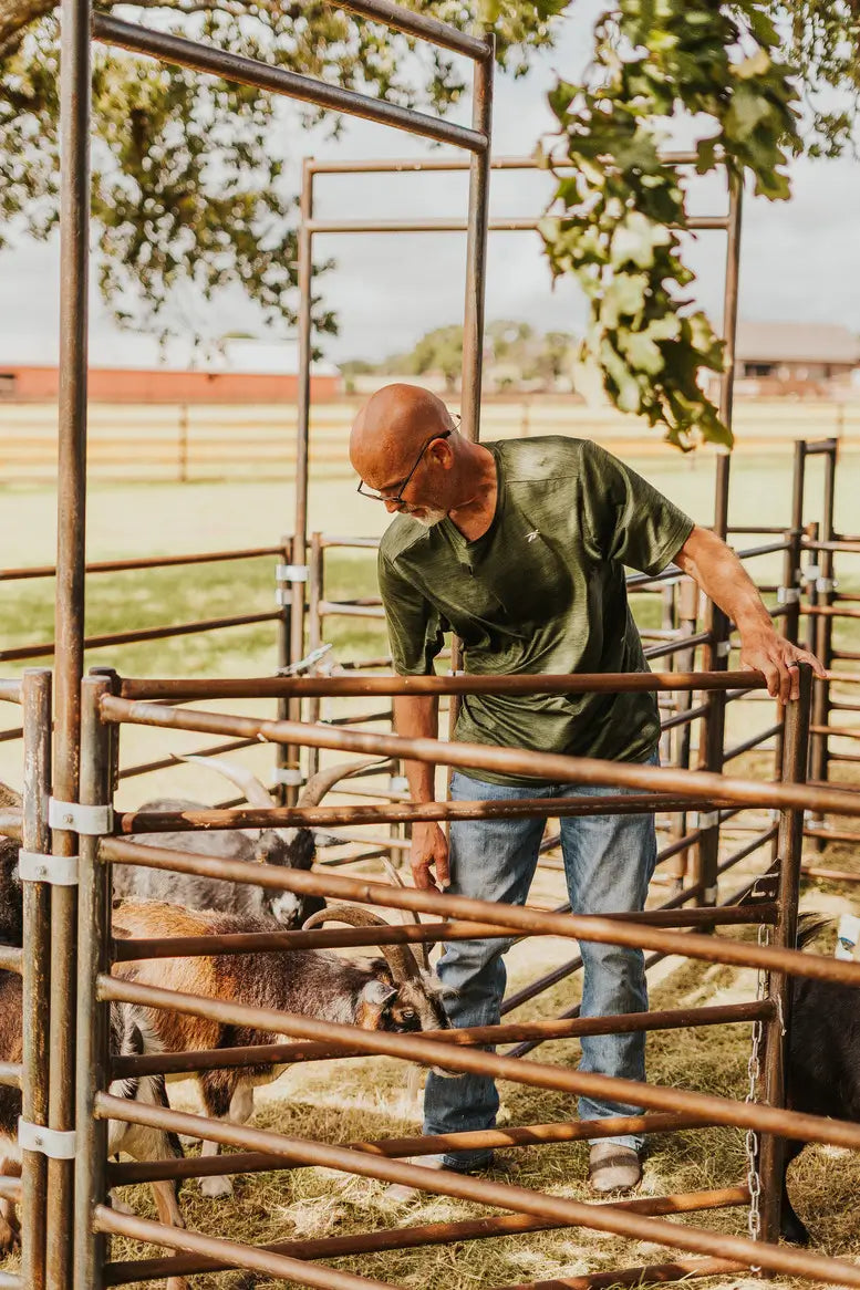 Man in a green shirt with goats in a pen
