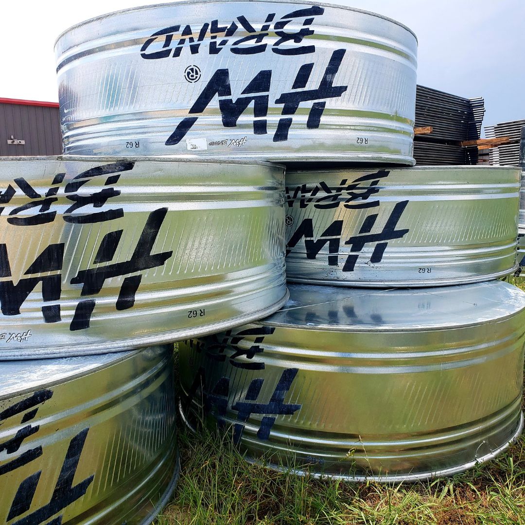 Stack of metal stock tanks with livestock fencing in background