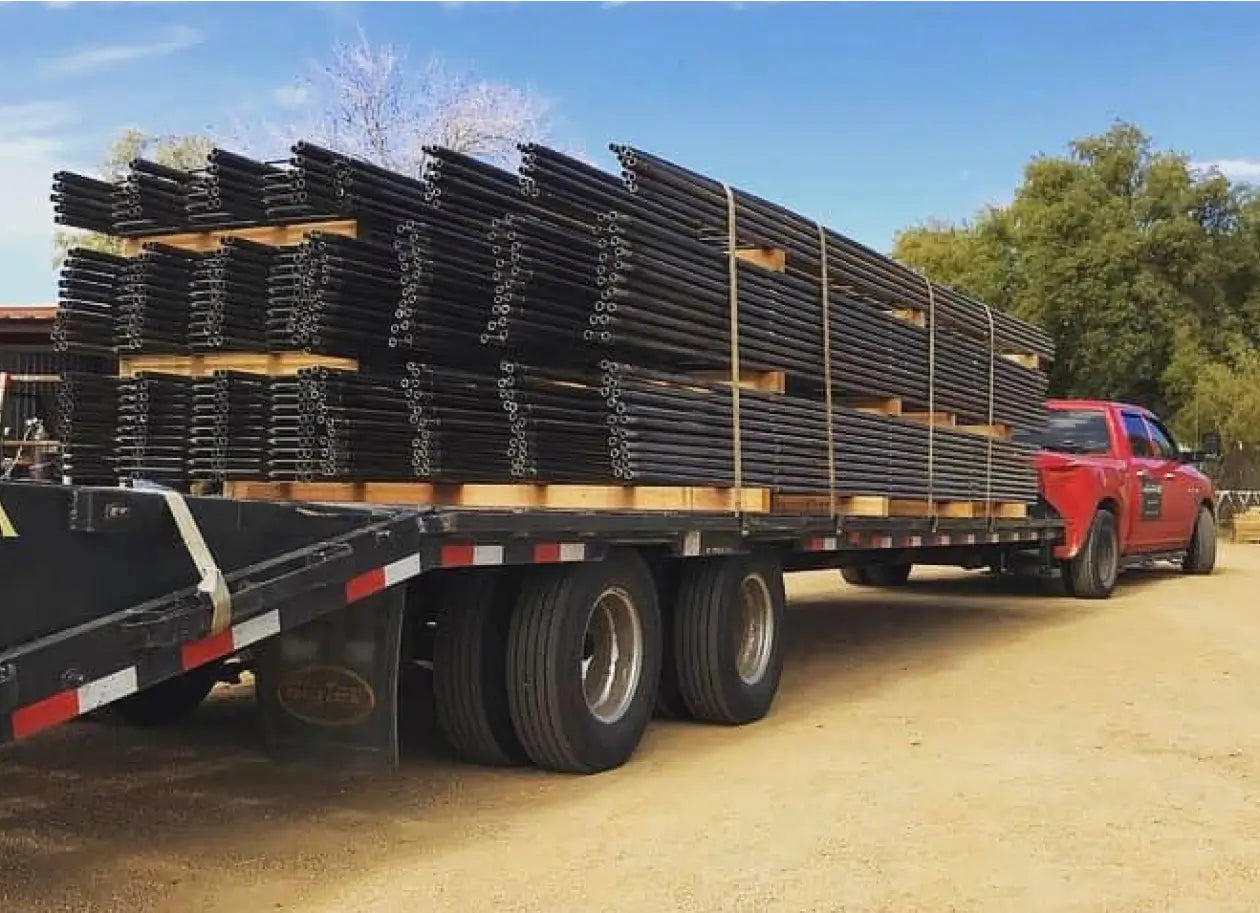 Flatbed trailer loaded with pipes secured for transportation.